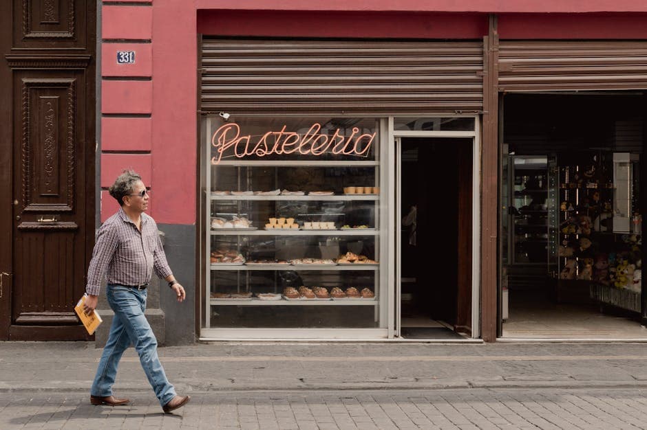 A man walks past a bakery with a 'Pastelería' sign in Heroica Puebla de Zaragoza, Mexico.