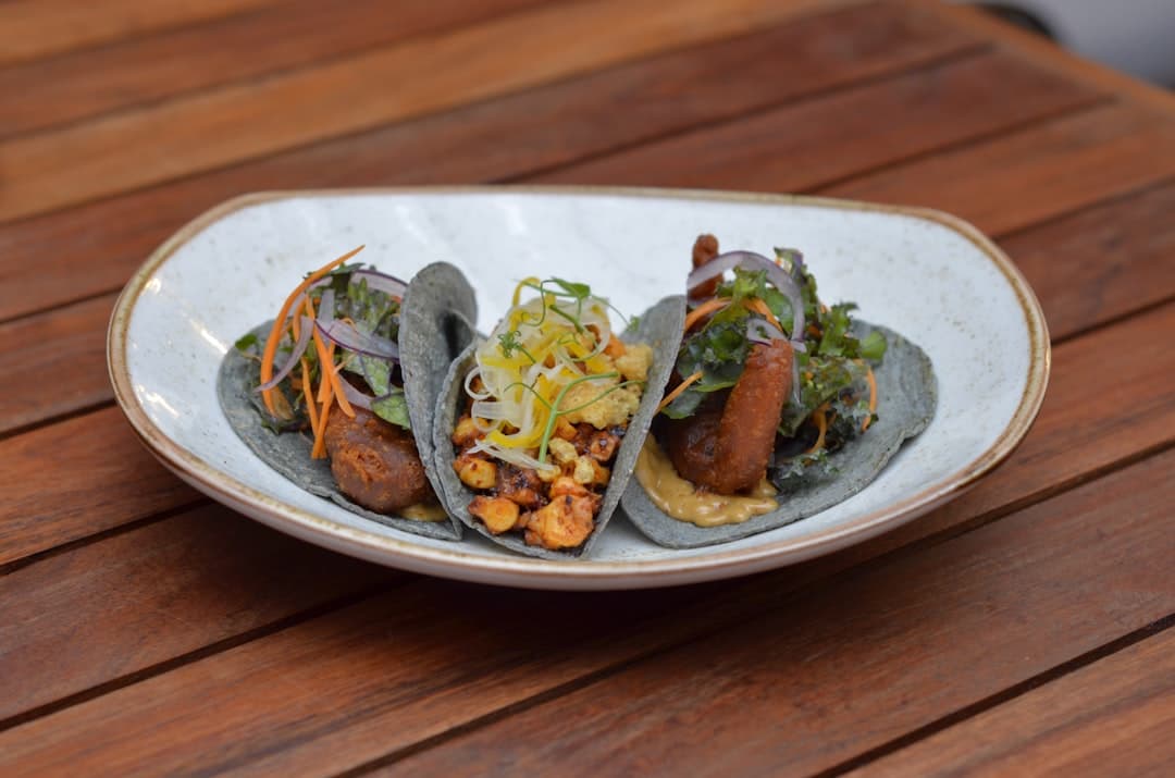 a white plate topped with three tacos covered in toppings