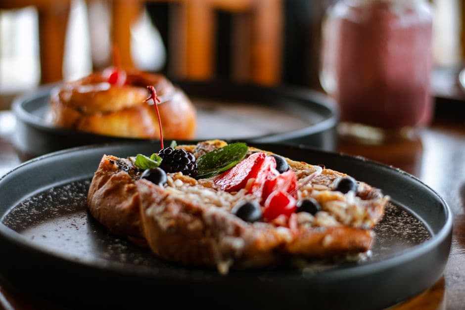 Close-up of a delectable pastry served with fresh fruits on a black plate.