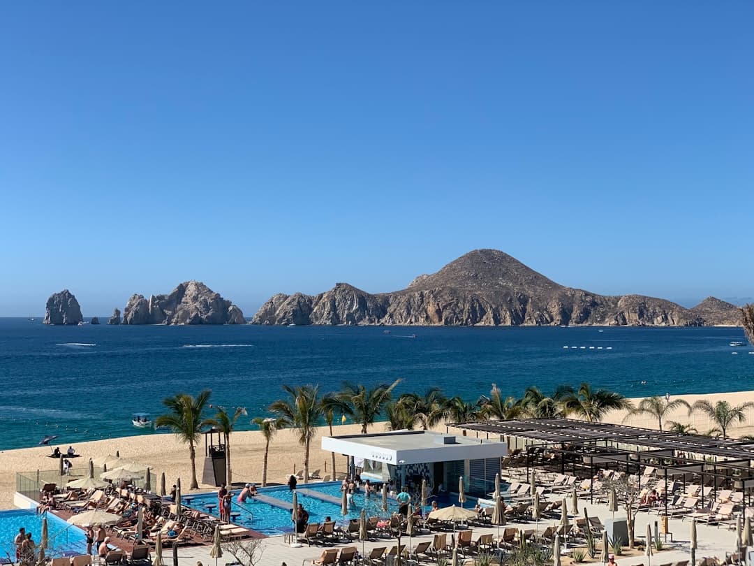 An aerial view of a beach with a pool and mountains in the background