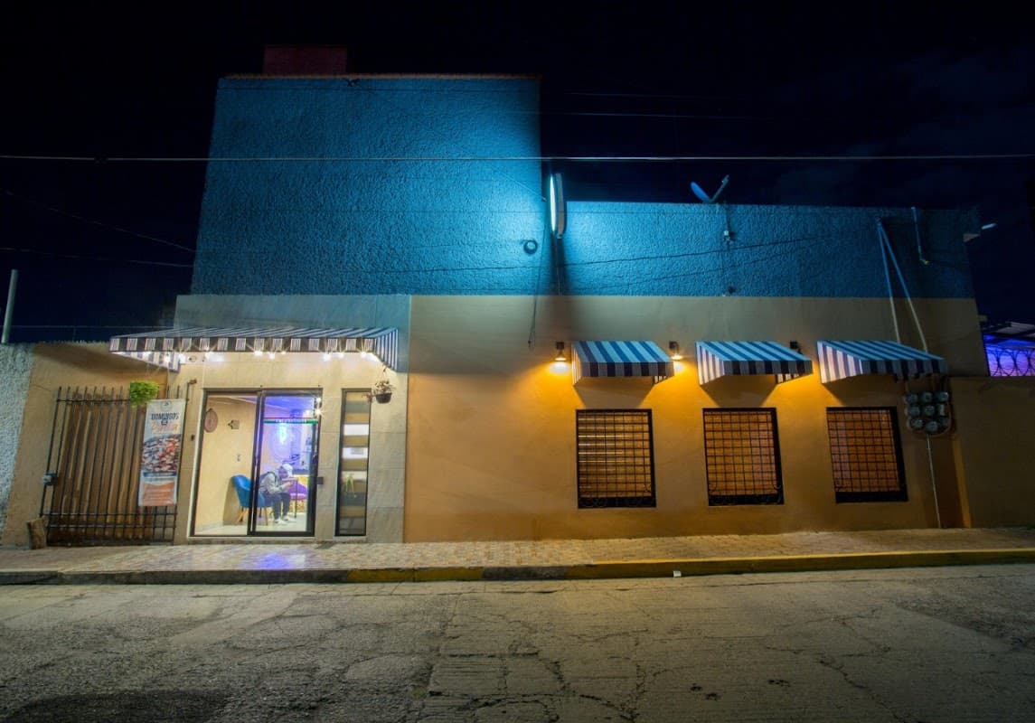 Buffa Wings con alitas crujientes y micheladas en la barra — interior con luces neón y ambiente de música alta