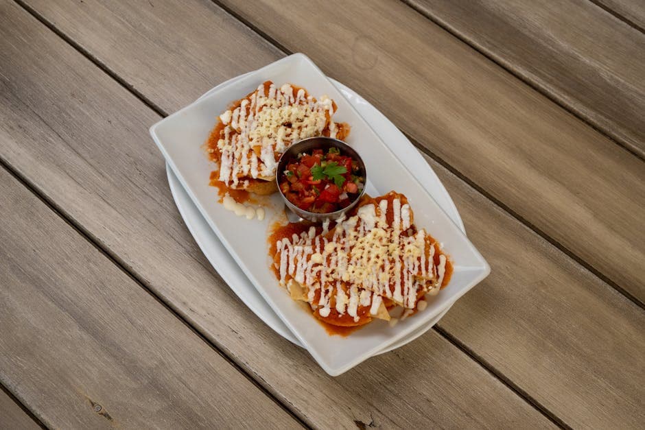 Delicious Mexican enchiladas topped with cheese and salsa, served on a wooden table.