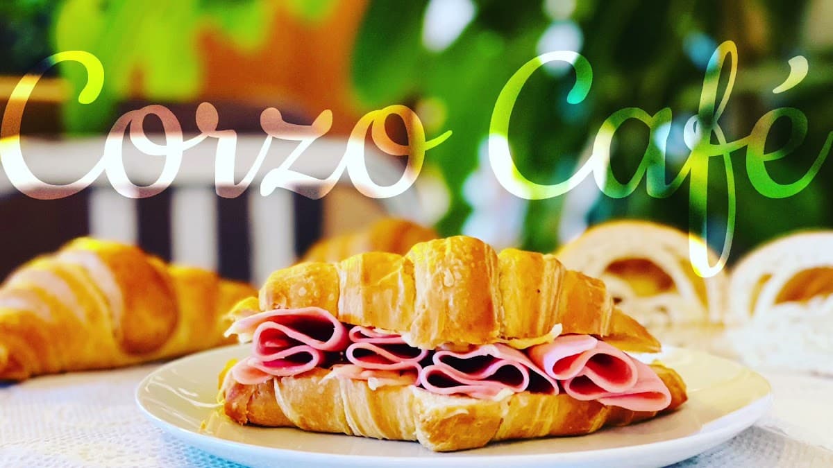Exterior of Corzo Café on Plaza Juárez with its bright signage and a table set with a steaming café de olla and a plate of pan dulce