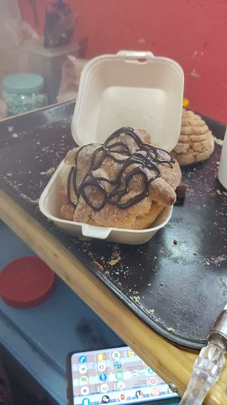 El Rey de Las Conchas Chimalhuacán — close-up of a colorful raspado topped with fresh fruit and a cone of conchitas on the counter