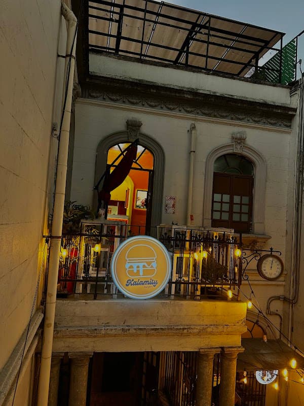 Fachada de Kalamity Burgers en Coahuila 49, con letrero iluminado y clientes en la acera