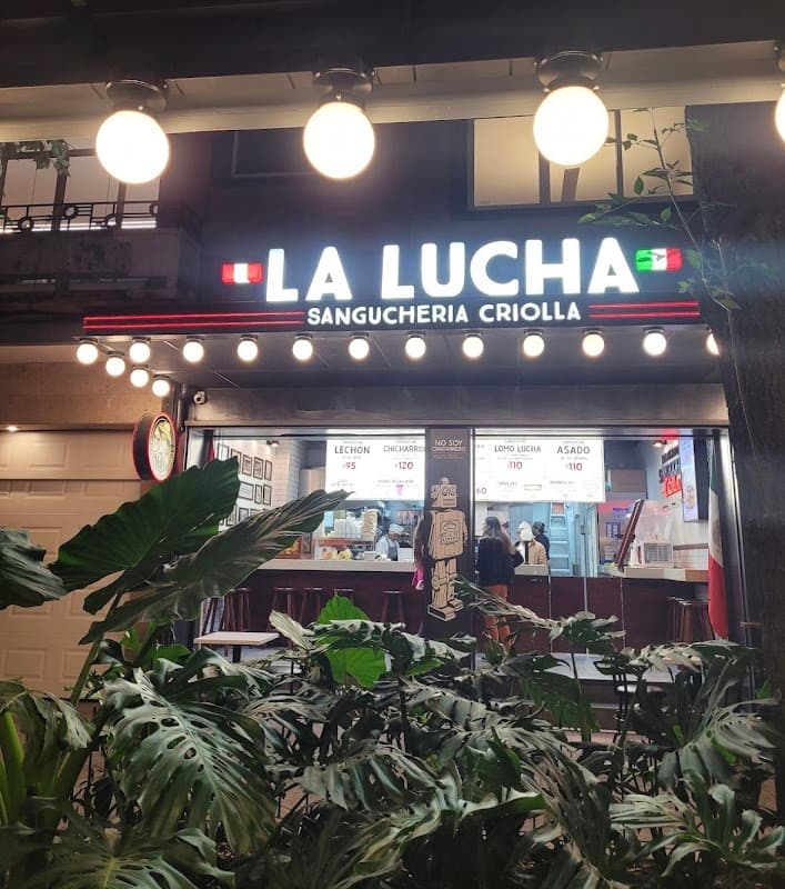 Frente de La Lucha Sangúcheria Criolla Polanco en Av. Emilio Castelar, con la fila de clientes y el letrero iluminado
