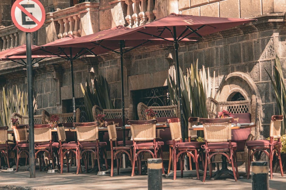 Sunlit outdoor cafe with red umbrellas and chairs in Ciudad de México showcasing local charm.
