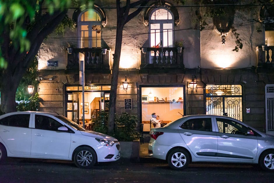 Illuminated café scene on a quiet street in Ciudad de México with parked cars.