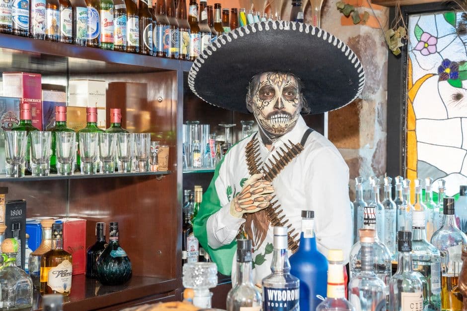 Colorful Day of the Dead themed bar setting in Ciudad de México with traditional attire.