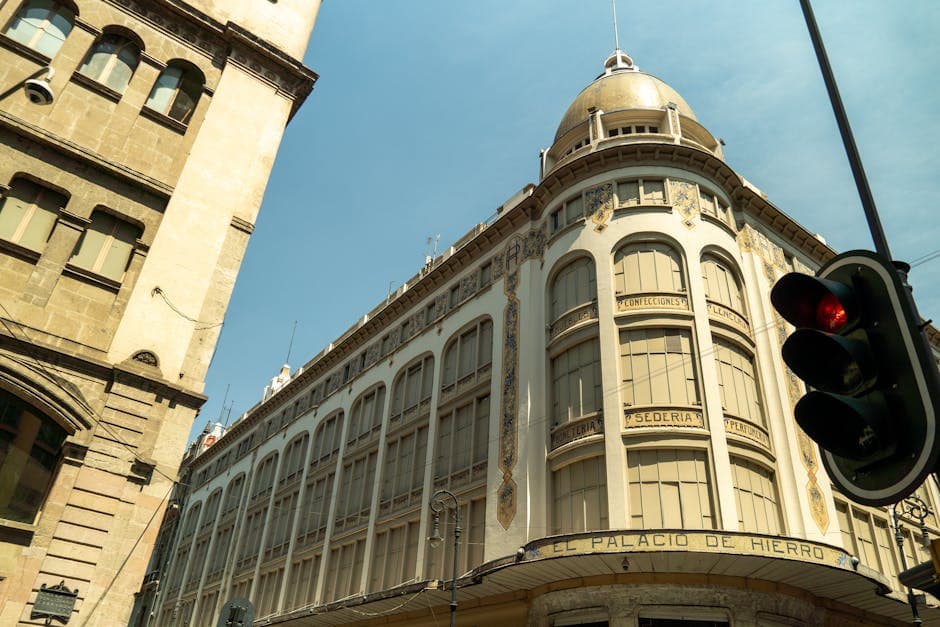 Low angle view of El Palacio de Hierro in Mexico City with urban traffic light.