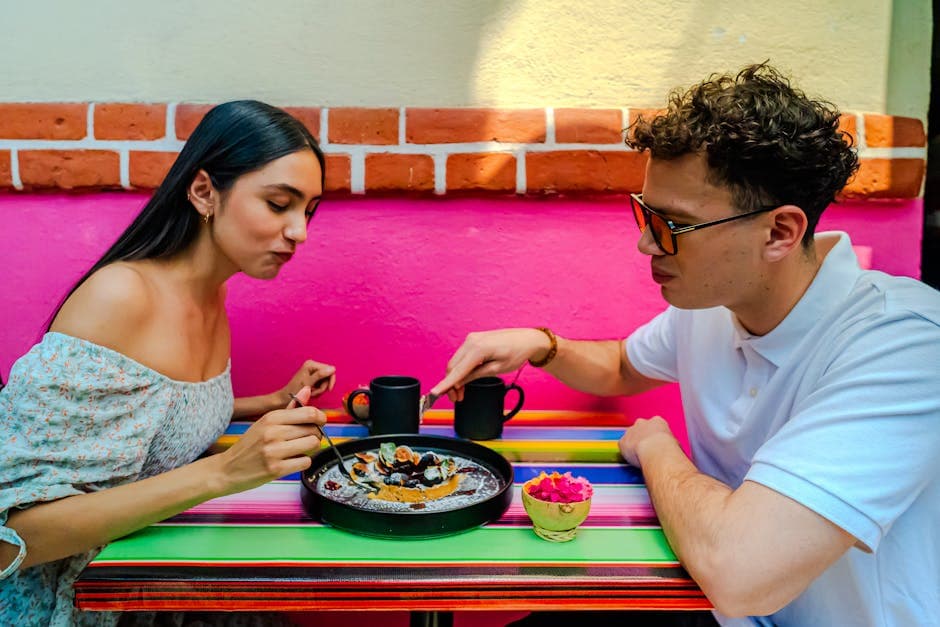 A couple enjoys a dessert at a colorful cafe table in Ciudad de México, capturing a vibrant lifestyle moment.