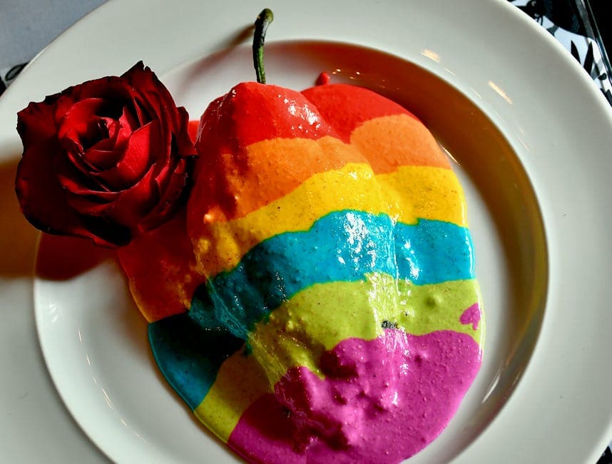 A vibrant plate of rainbow-colored Chiles en Nogada with a red rose garnish, creating an artistic culinary scene.