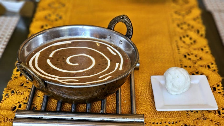 A delicious Indian Dal Makhani served with butter and naan on a vibrant yellow tablecloth.