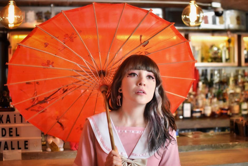 Portrait of a woman with a red parasol in a stylish café in Mexico City, capturing elegance and charm.