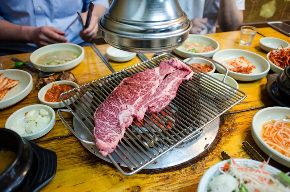 Close-up of Korean barbecue with marbled beef grilling amidst traditional side dishes.