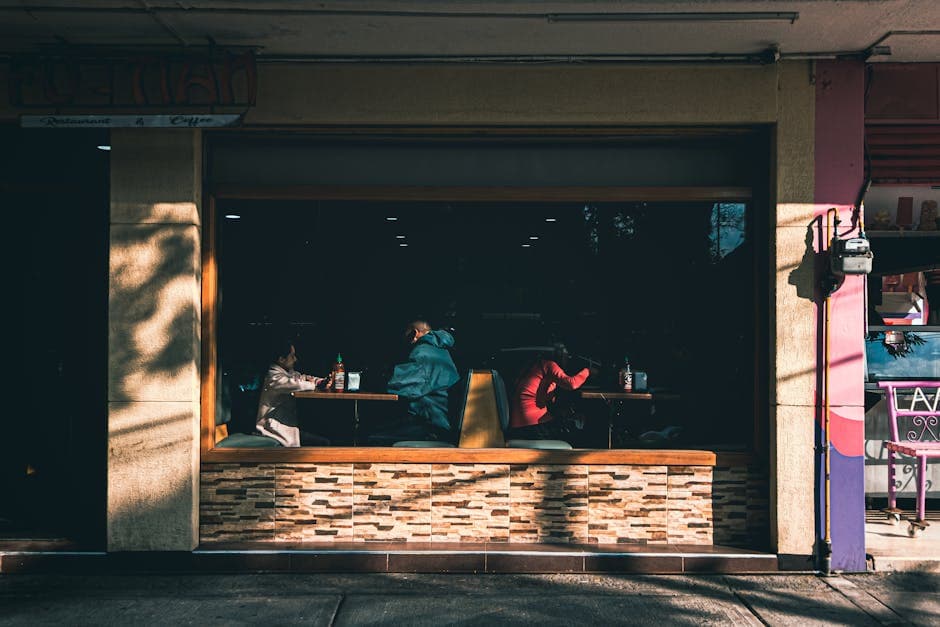 People dining inside a cozy cafeteria in Ciudad de México, viewed through a large window.