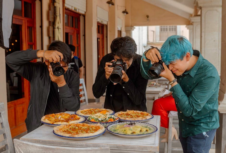 Three photographers taking pictures of a variety of pizzas at an outdoor restaurant in Lerma, Mexico.