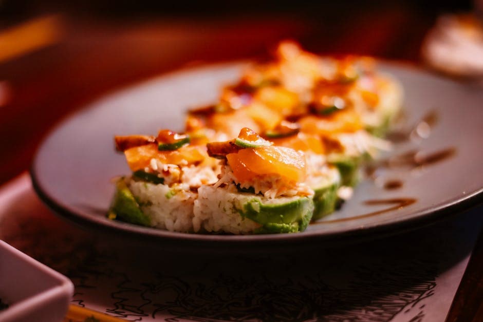 Gourmet sushi rolls topped with fresh salmon and avocado on a stylish plate.