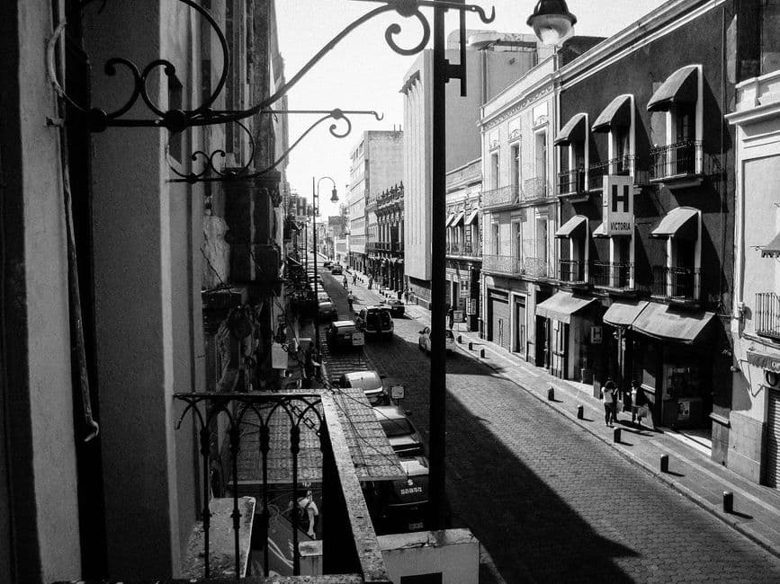 Black and white street view of historic Puebla, Mexico with colonial architecture.
