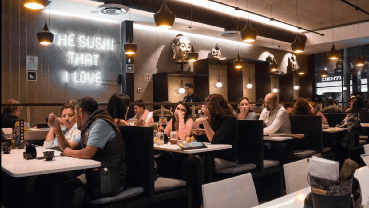 Exterior de Waraku Comida Japonesa con su letrero rojo y una mesa de bento al frente