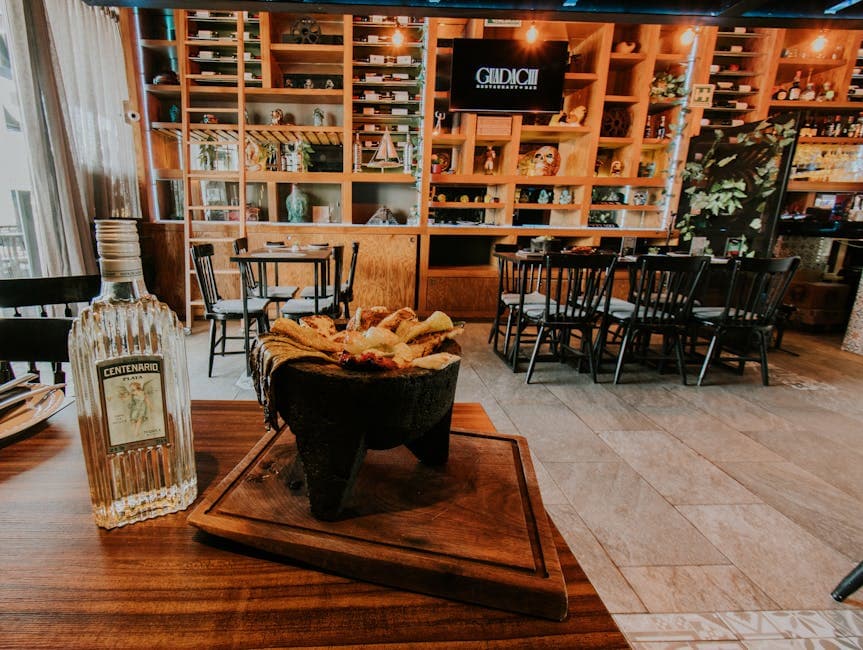 Mexican restaurant interior with tequila bottle and traditional dish on a wooden table.