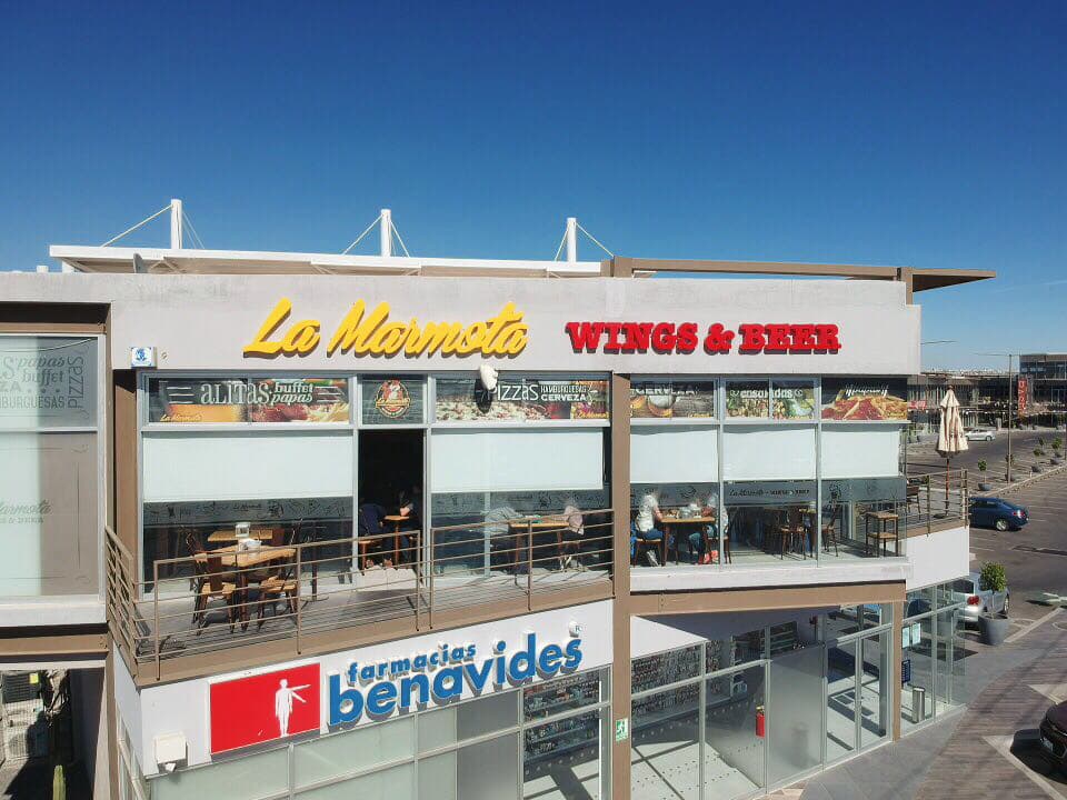 Exterior iluminado de La Hamburguesía en Av. Candiles, con su letrero neón y una hamburguesa jugosa en primer plano