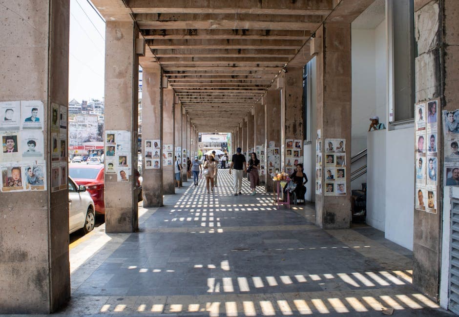 Urban walkway in Acapulco with posters and bold shadows, a vibrant cultural scene.