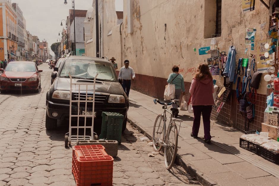 Urban street life in Puebla, Mexico, featuring pedestrians, cars, and street vendors.