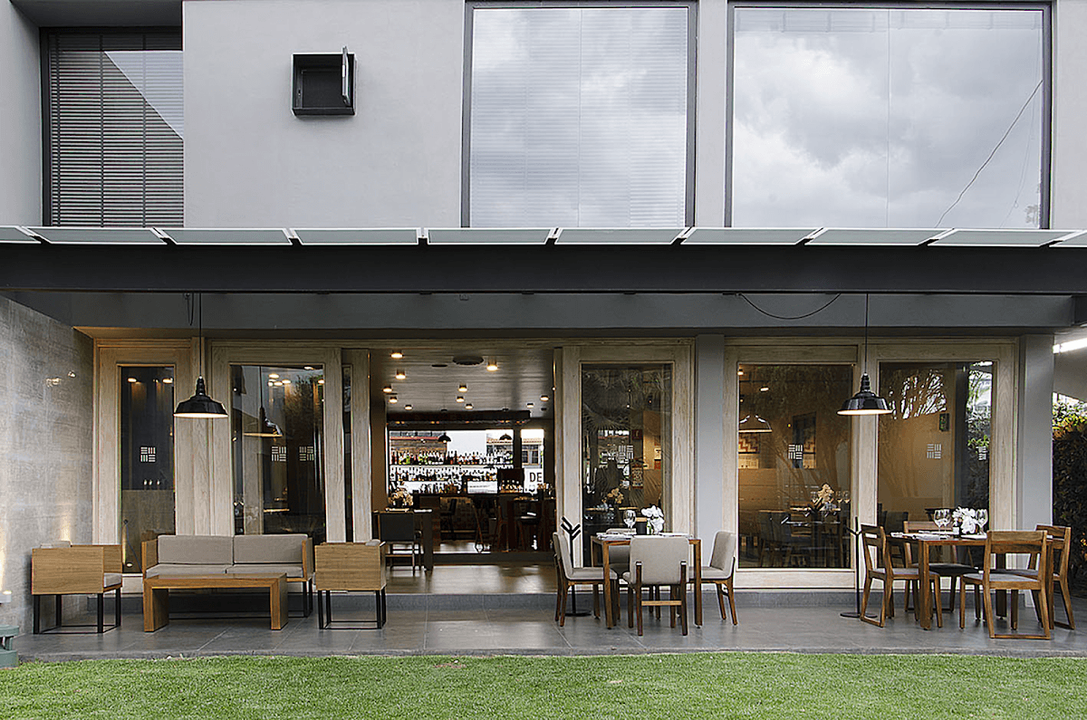 Las Alitas Irapuato exterior con su señal luminosa y una bandeja de alitas doradas sobre una mesa de madera.