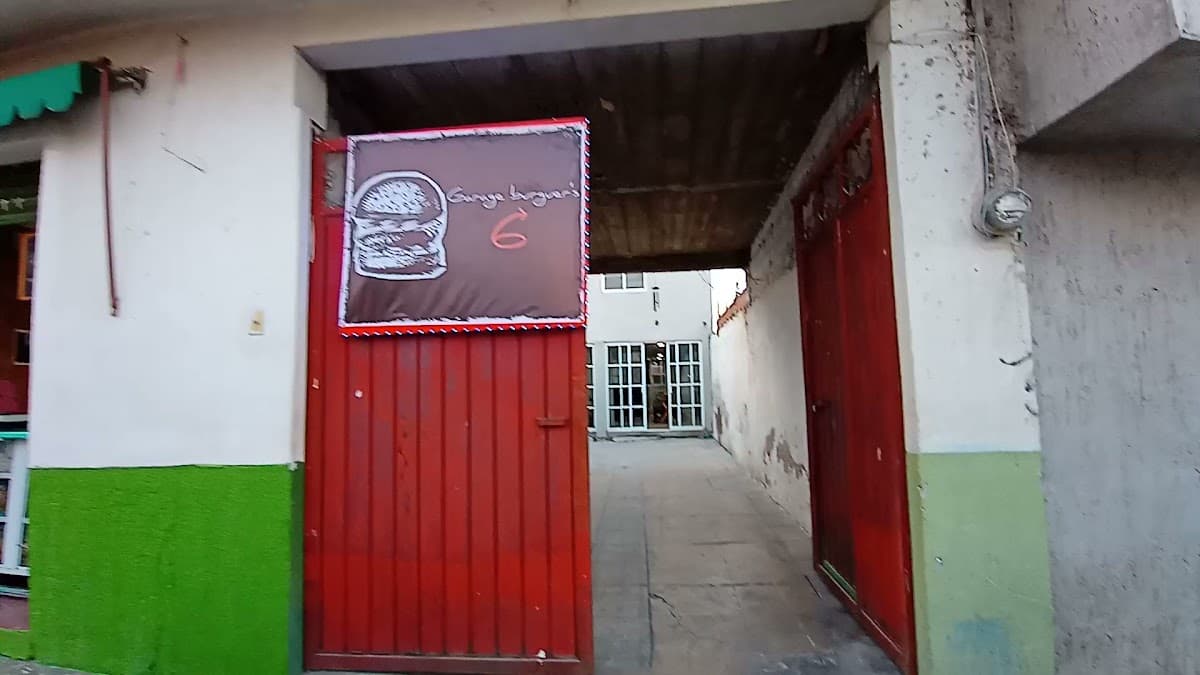 Exterior de Garage burguer's 6 con su letrero rojo y una bandeja de hamburguesas jugosas sobre la mesa