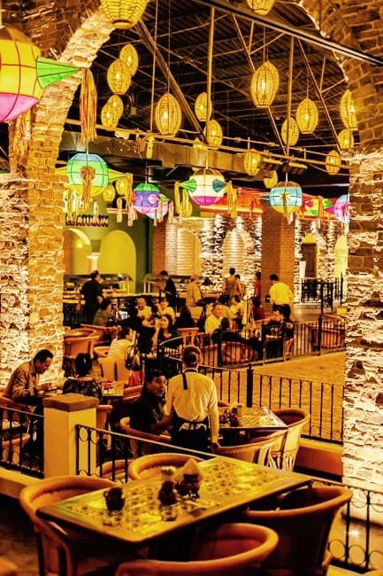 Frente del restaurante El Buen Sazón en Ramón Rivera Lara, con su letrero rojo y mesas al aire libre, clientes disfrutando de chilaquiles