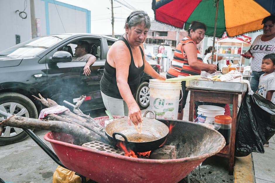 Street vendor frying food outdoors in Simbal, Perú, with a colorful setup.