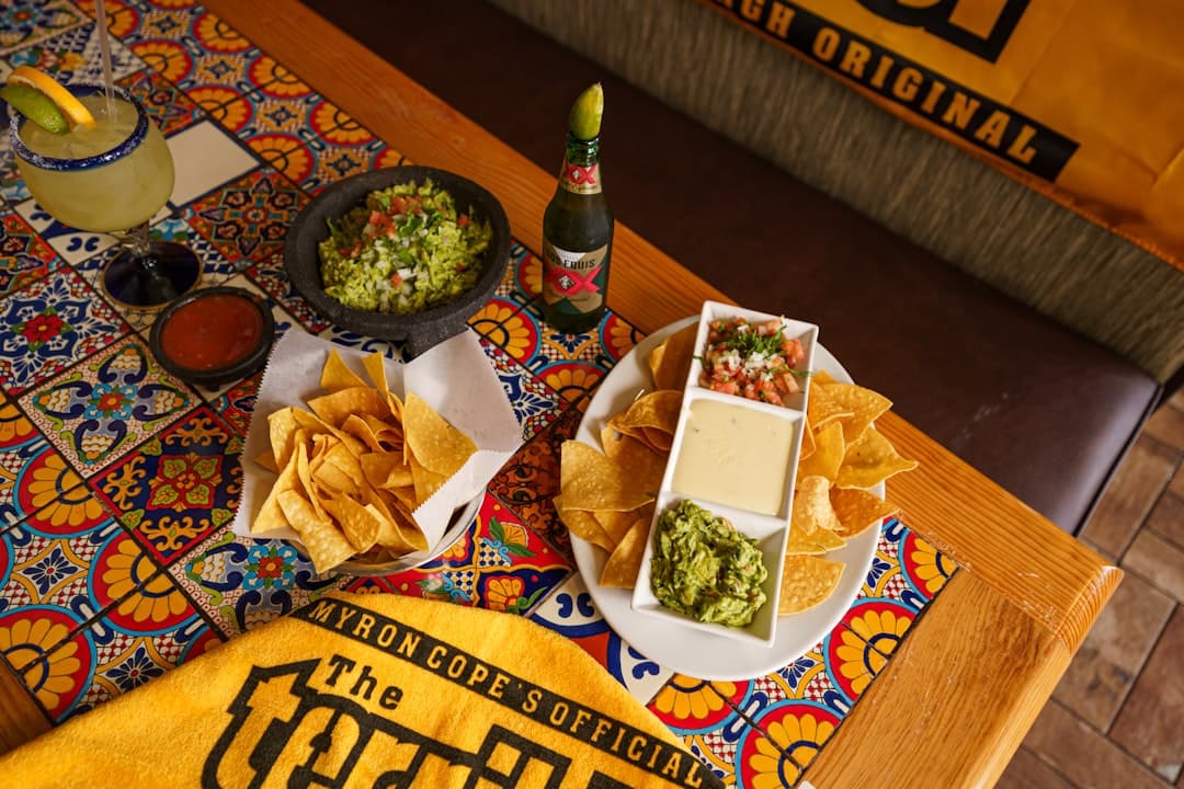 a table topped with plates of food and a bowl of guacamole