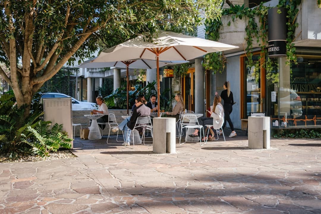 People enjoying lunch at an outdoor cafe under umbrellas.