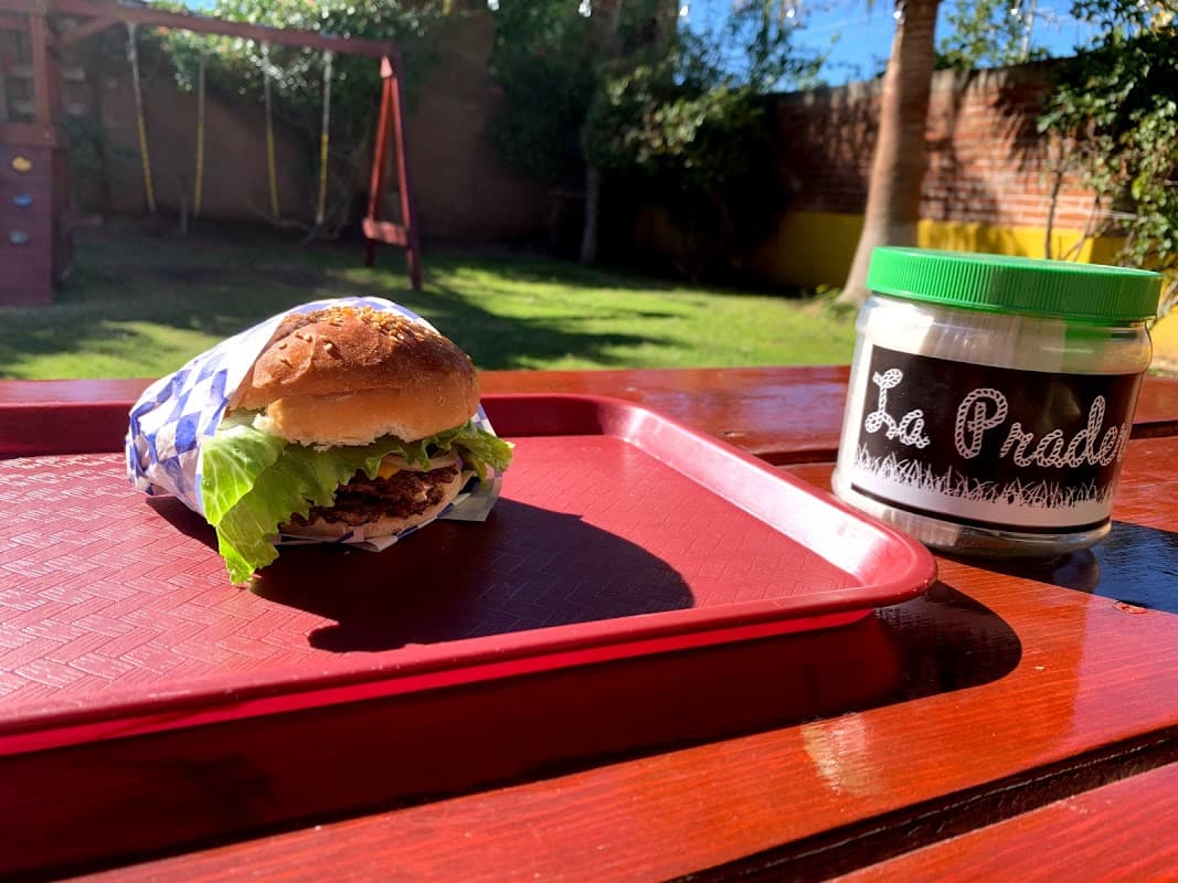 Carnísimo Burgers con su letrero iluminado y una hamburguesa jugosa sobre la mesa exterior