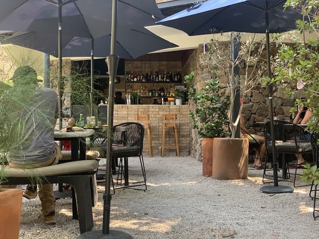 Exterior de Restaurante Casa Colibrí en Plaza Principal, mostrando su fachada iluminada y la terraza con botellas de mezcal bajo la luz nocturna