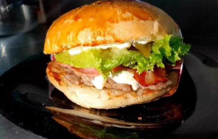 Fachada azul de Isabellas Kitchen con letrero blanco y clientes en la fila en la mañana
