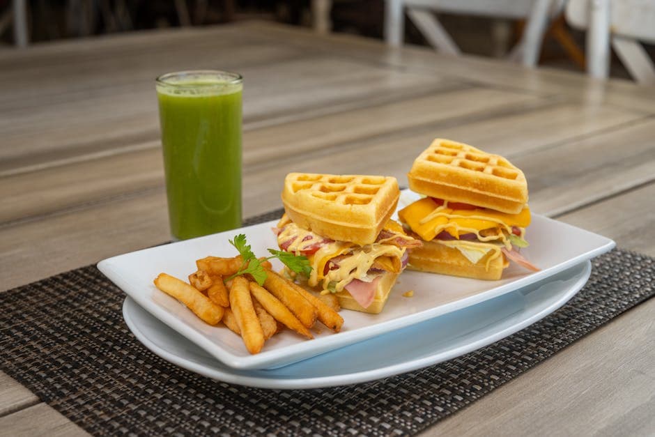 Savor a waffle sandwich with fries and a refreshing green juice, perfect for dining outdoors.