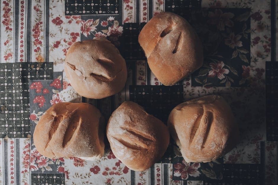 Top view of homemade bread rolls on a floral tablecloth, captured in ambient lighting.
