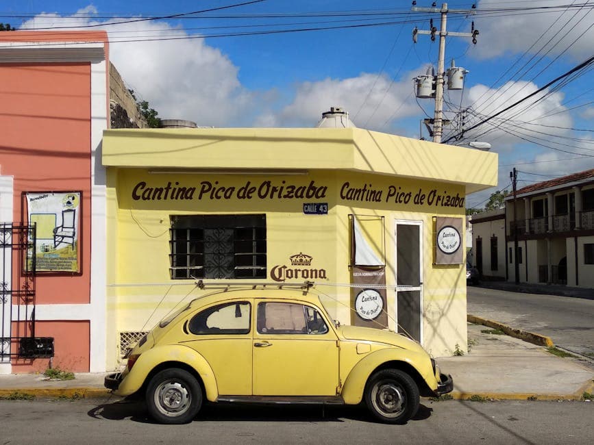 A classic yellow Beetle car parked in front of Cantina Pico de Orizaba in Mérida, Mexico.