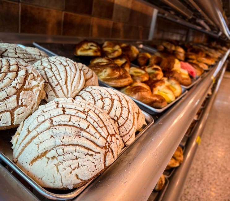 Freshly baked conchas and other pastries on trays in a Mexican bakery.