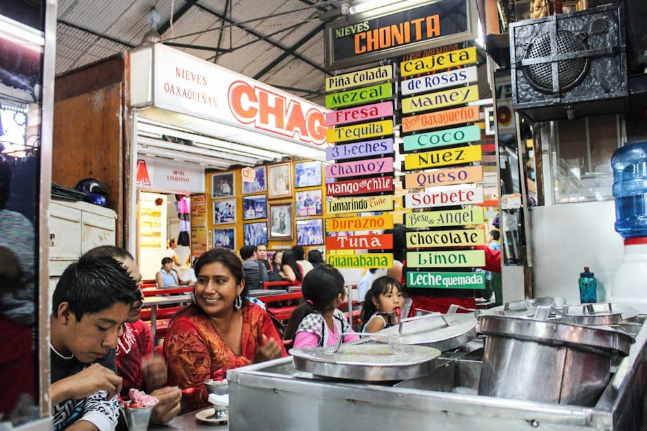 A lively Mexican ice cream shop with colorful signs and diverse customers enjoying treats.