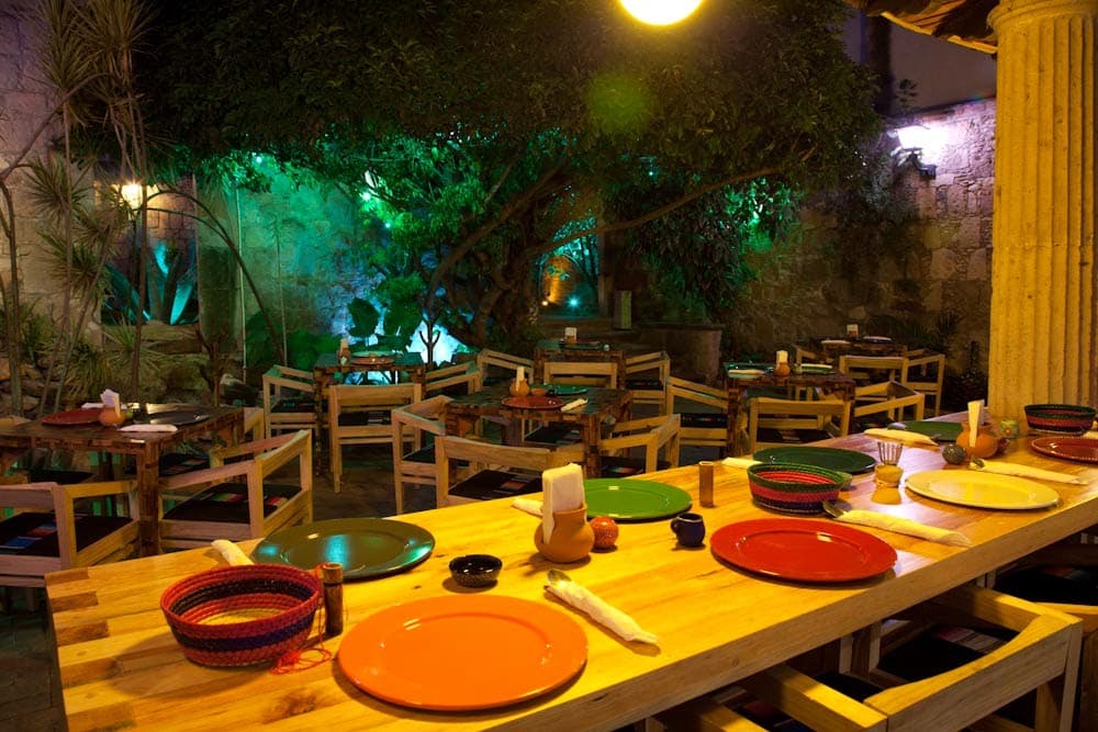 Fachada de Tata Mezcalería + Cocina en Bartolomé de Las Casas, con su puerta de madera tallada y luces cálidas al atardecer