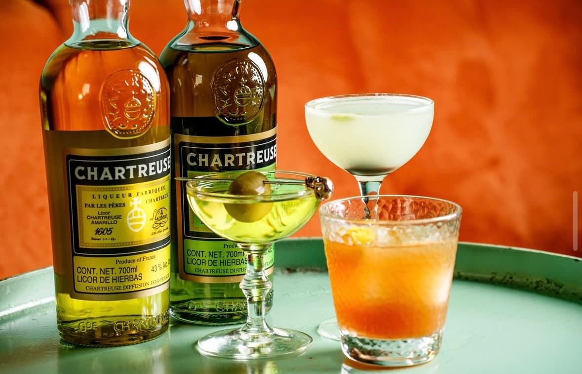 Xaneque Cocktail Room — interior con barra de cobre, copas brillantes y bartender preparando un mezcal old fashioned