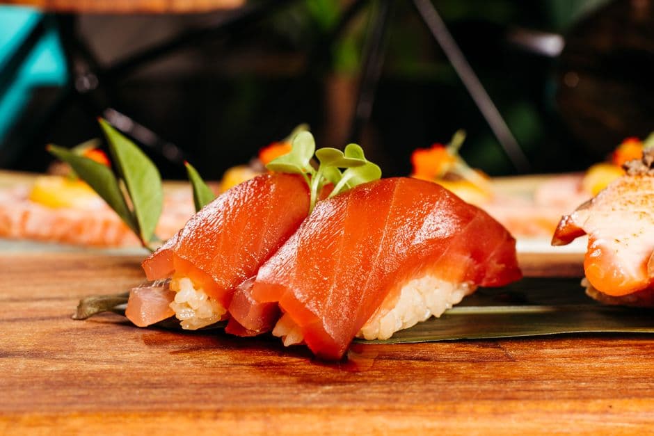 Delicious slices of salmon nigiri sushi served beautifully on a wooden platter with garnish.