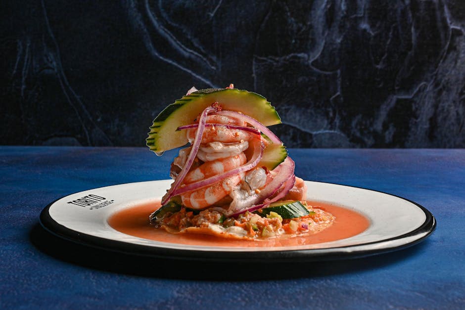 Appetizing seafood tower of shrimp with red onion and cucumber on a plate.