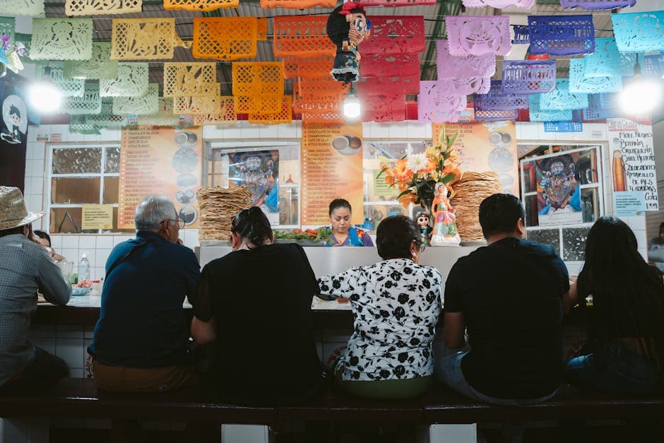 People enjoy a traditional meal under colorful papel picado decorations in Oaxaca, Mexico.