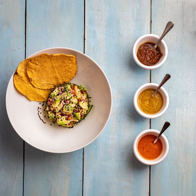 Top-down view of Mexican dish with sauces on a rustic blue table.