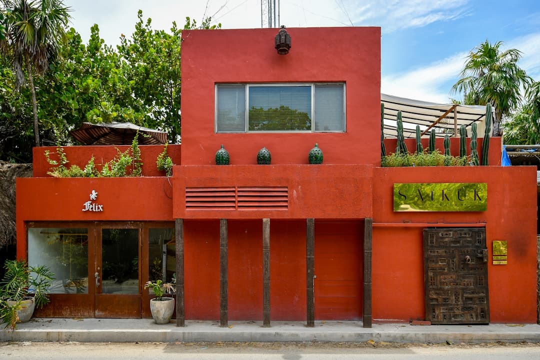 A bright red building with wooden columns and plants.