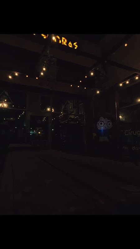 Interior de Las Escobas con mesas decoradas al estilo Hogwarts, luces tenues y una jarra de butter beer en primer plano